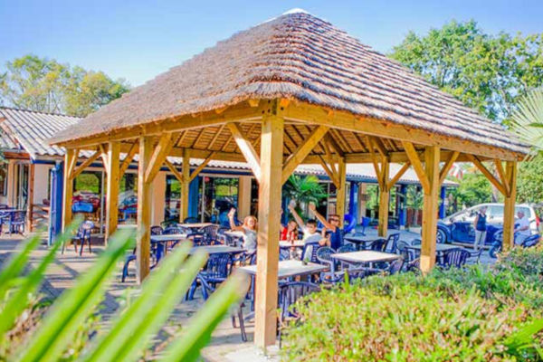 Espace repas ombragé avec tables sous un chalet